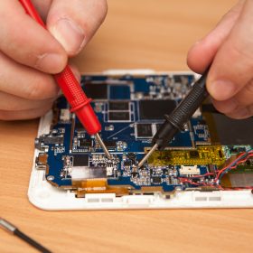 repairer is looking for damage to the tablet using a multimeter.